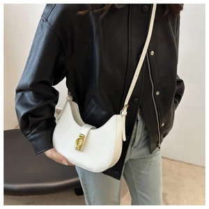 Close-up of a white hobo bag with a golden metal buckle worn with a black leather jacket