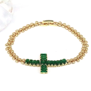 Macro detail of gold cross bracelet with emerald green zircon inlay and lobster clasp