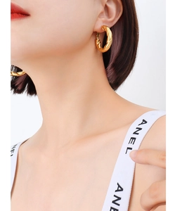 Detail of French twisted hoop earrings in 18k gold plated stainless steel on model