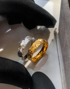 Close-up of 18k gold and silver rings with hammered texture held by black gloves