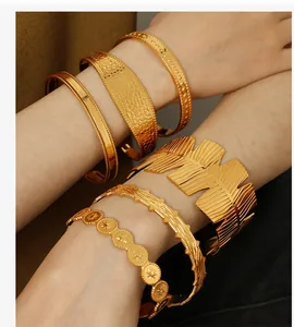 Close-up of stacked gold adjustable bangles with leaf and star patterns on a model's wrist