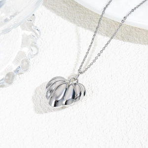Detailed view of silver shell-shaped pendant on textured white surface with glass