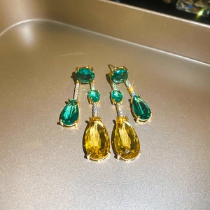 Vue détaillée de boucles d'oreilles en zircon jaune et vert sur plateau doré