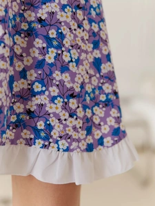 Close-up of floral purple dress with small daisy prints and white ruffled hem detail