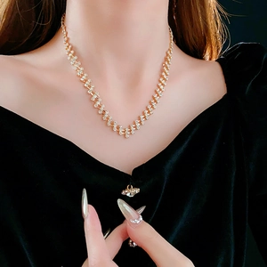 Close-up of geometric gold chain necklace with diamond accents on a model's neck