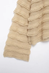 Detail of tiered ruffles on a beige mohair knit sweater with soft texture and transparency