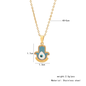 Detail view of gold Hamsa hand pendant with blue enamel eye and stainless steel specs