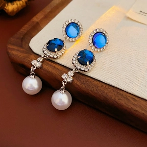 Dettaglio della collana di cristallo blu con perla bianca su sfondo di legno rustico