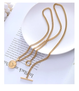 Detail view of gold toggle clasp and engraved gun pendant on a chunky cuban link chain