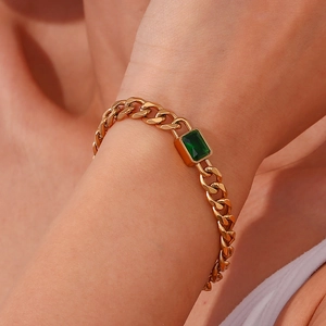 Close-up of 18K gold plated cuban link bracelet featuring a central emerald green zircon