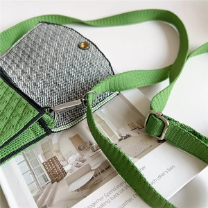 Macro view of green knitted mini bag featuring black and white checkered fabric and silver clasp