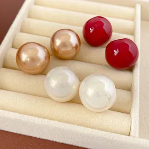Luxuriöse Muschelperlen-Ohrstecker in Gold, Rot und Weiß auf Samt-Displayständer