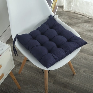 Detail of dark blue thickened square chair cushion with fixing straps on a white chair