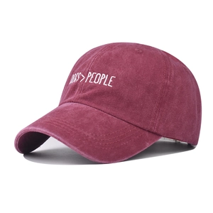 Detail view of the embroidered slogan Dogs People on a vintage washed burgundy baseball cap