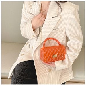 Detail of orange transparent jelly bag with quilted texture and gold chain strap