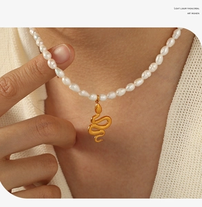 Detail of vintage snake pendant necklace with natural baroque pearls on model's neck