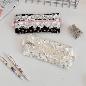 Close-up of quilted pencil cases with lace trim and floral patterns on white desk