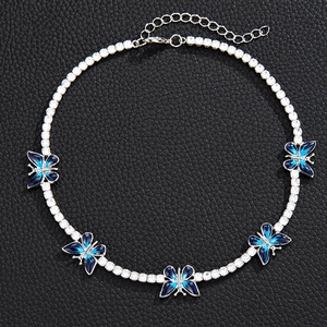 Macro detail of silver zircon tennis chain necklace with blue enamel butterfly charms