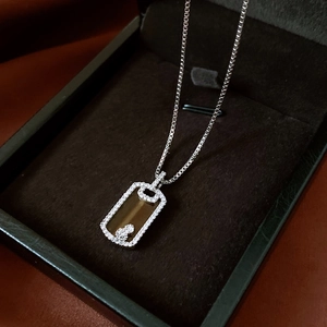 Détail d'un pendentif rectangulaire argenté orné de cristaux et d'un motif d'ours