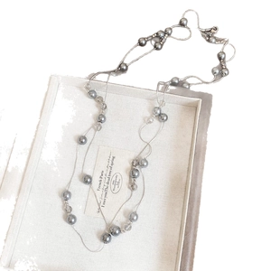 Tiger eye and gray pearl layered necklace displayed on a vintage jewelry tray