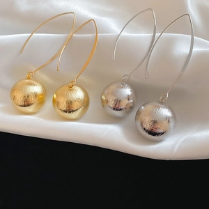 Macro detail of gold and silver textured round ball earrings on white silk