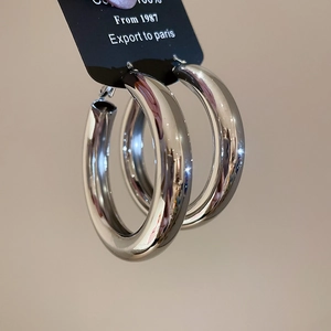 Close-up of thick silver polished hoop earrings on black display card with glossy finish