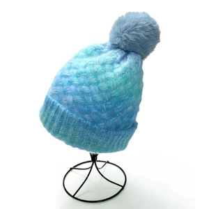 Detailed cable knit texture of gradient blue beanie with fluffy matching pom-pom