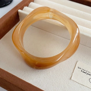 Detail of amber translucent resin geometric bangle with wave design in a jewelry box