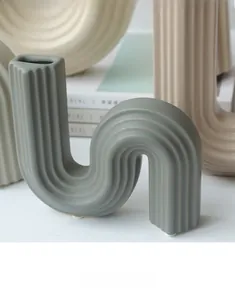 Détail du vase en céramique vert gris en forme de S avec texture côtelée et design ondulé
