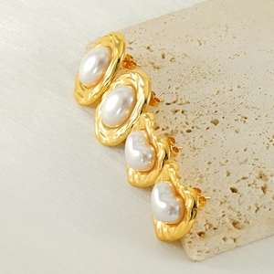 Detailed view of vintage gold ripple oval stud earrings with large pearl accents