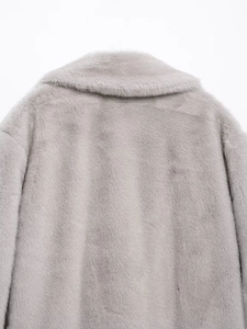 Detailed close-up of light gray faux fur coat neckline and soft texture on white background