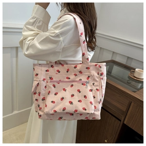 Pink corduroy strawberry tote bag featuring a front zipper pocket and side compartments
