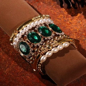 Vintage gold bracelet set with white pearls and green oval gemstone on a display