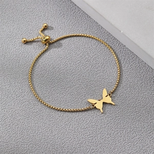 Detail of a golden box chain bracelet featuring a butterfly charm and adjustable bolo clasp