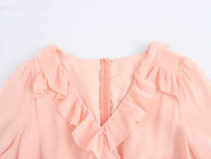 Close-up of V-neckline with ruffle details and hidden back zipper on pink chiffon dress