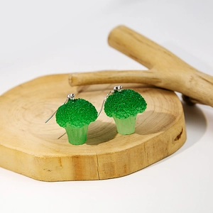 Creative resin broccoli shaped drop earrings with silver hooks on rustic wood display