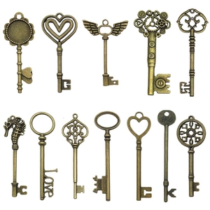 Set of 12 vintage bronze alloy key pendants with heart and wing motifs on white background