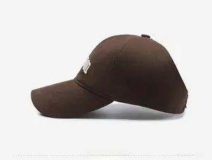 Detail view of brown cotton baseball cap showing white 3D embroidery on the side