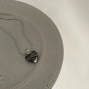 Macro shot of silver snake chain featuring a zebra pattern heart pendant on a ceramic plate