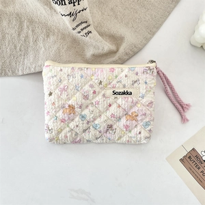 Detail of floral quilted cotton pouch featuring puppy print and a pink zipper pull