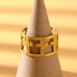 Detail of gold wide band ring with hollow cross pattern and hammered texture on display