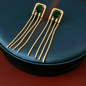 Close-up of vintage gold earrings with green square zircon and long chain tassels