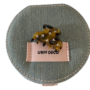 Elegant tortoiseshell acetate hair claw with sparkling rhinestones on a denim display