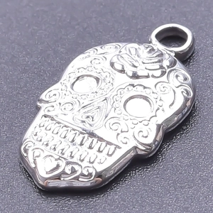 Macro shot of stainless steel sugar skull pendant with intricate floral engravings