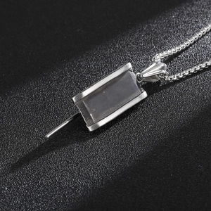 Macro detail of silver stainless steel tank pendant on a box chain over black texture