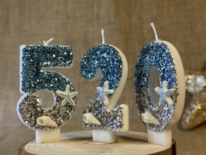 Detailed view of ocean-themed birthday candles number 520 with blue glitter and seashells