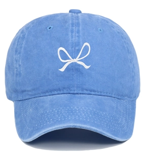 Close-up of blue washed cotton baseball cap featuring detailed white embroidered bow design