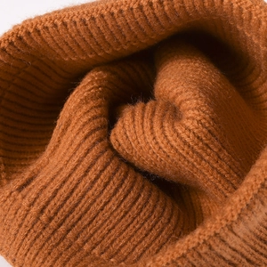 Winter knitted beanie featuring a textured ribbed design and a warm dark orange finish