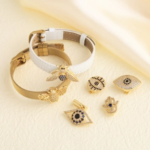 Macro shot of evil eye charms and golden mesh watch strap on soft silk background