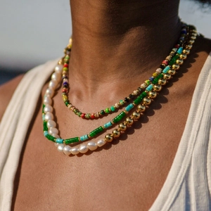 Close-up of layered bohemian necklaces with colorful beads and pearls on a model